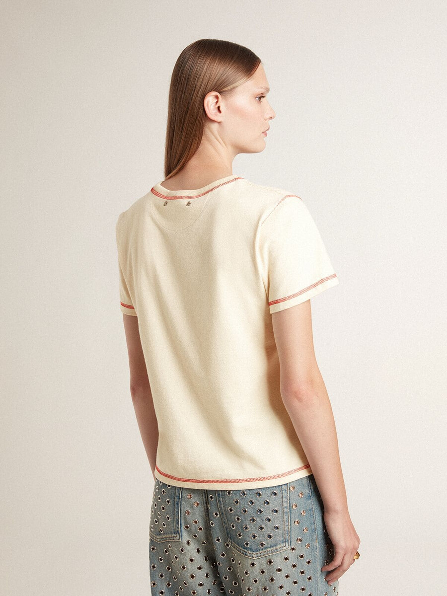 色あせた赤のアクセントが付いたクリーム色のレディースtシャツ
